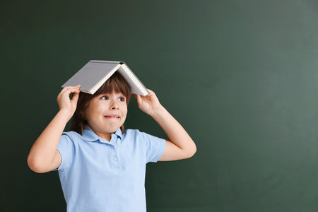 Back to school. Boy with book against chalkboard indoors, space for textの写真素材
