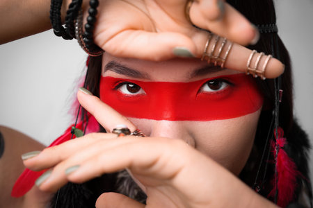 Shaman woman with face painting on light gray background, closeup