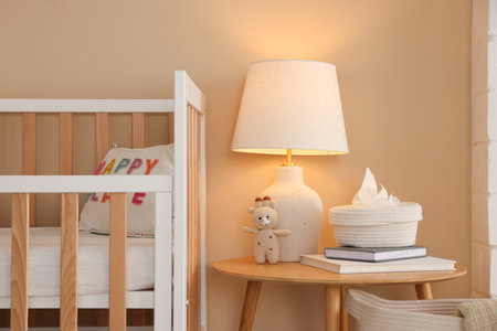 Crib, table, lamp and decor in stylish baby's roomの写真素材