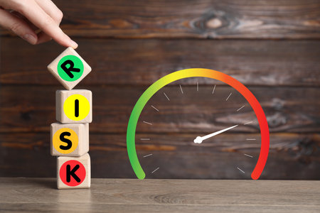 Woman making word Risk with wooden cubes at table, closeup. Scale displaying level of riskの写真素材
