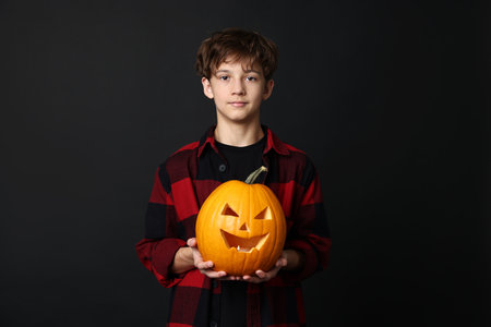Halloween celebration. Boy with jack o'lantern pumpkin on black backgroundの写真素材