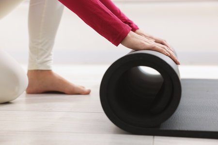 Woman unrolling mat in yoga studio, closeupの写真素材