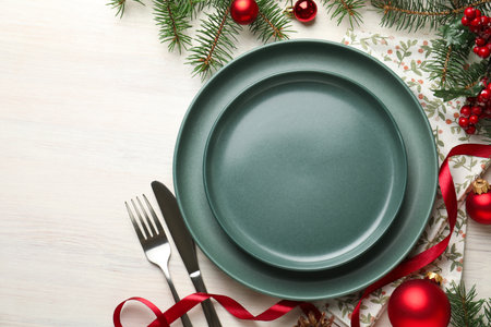 Festive table setting with Christmas decor on light wooden background, flat lay. Space for textの写真素材