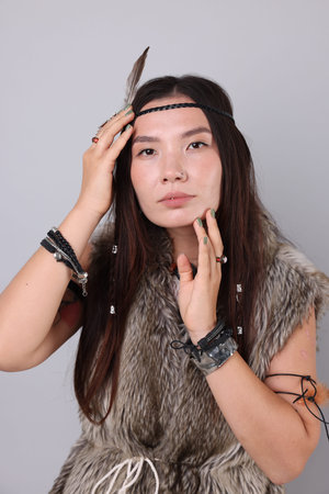 Shaman woman in feather headdress on light gray background