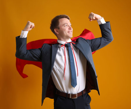 Businessman wearing superhero cape on yellow backgroundの写真素材