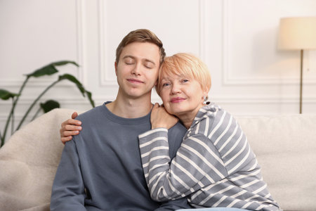 Mother and son hugging on sofa at homeの写真素材