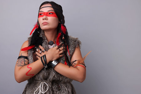 Shaman woman with face painting on light gray background, space for text