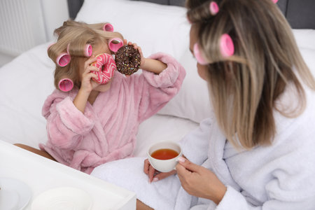 Mother and daughter having tea party on bed at homeの写真素材