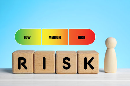 Risk word made of wooden cubes, scale and human figure against light blue backgroundの写真素材