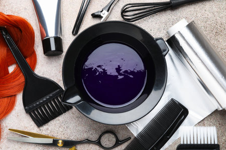 Hair dyeing product in bowl, lock of hair and different hairdresser's tools on light gray table, flat layの写真素材
