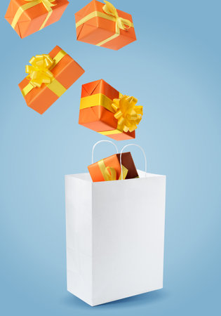 Many gift boxes falling into paper bag on light blue backgroundの写真素材