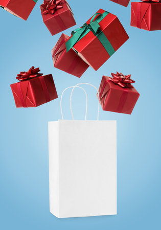 Many gift boxes falling into paper bag on light blue backgroundの写真素材