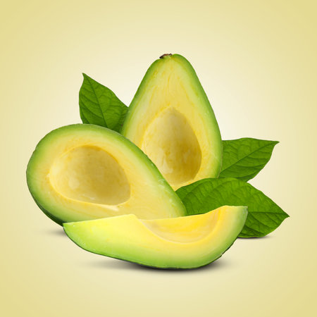 Fresh avocados and green leaves on beige backgroundの写真素材