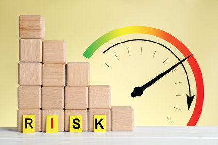 Scale with arrow indicating level of risk and wooden cubes against beige backgroundの写真素材
