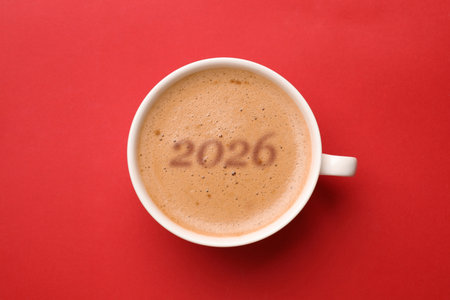 Hello New 2026 Year. Cup of coffee with numbers on red background, top viewの写真素材