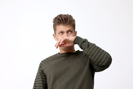 Young man suffering from bad smell indoors