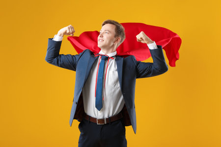 Businessman wearing superhero cape on yellow backgroundの写真素材