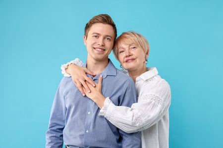 Mother hugging her son on light blue backgroundの写真素材