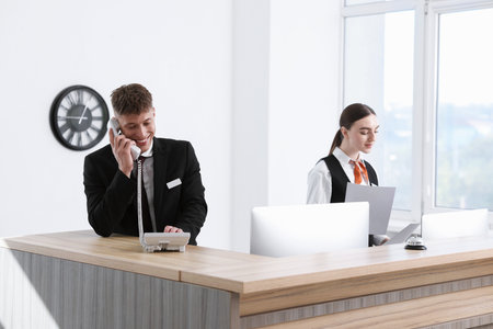Receptionist and hostess working at reception desk in hotelの写真素材