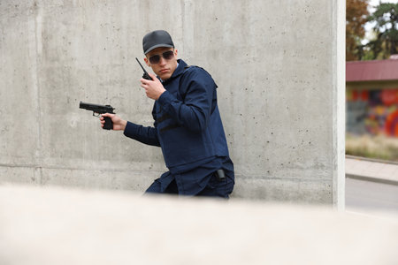 Police officer with radio and gun outdoorsの写真素材