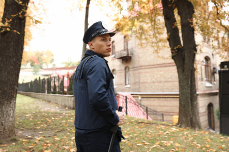 Police officer in bulletproof vest with baton at park. Space for textの写真素材