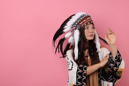 Shaman woman in native American Indian headdress on pink background, space for text