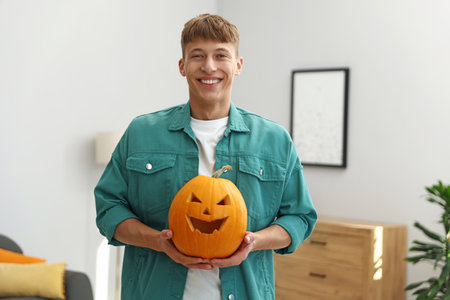 Halloween celebration. Man holding pumpkin with carved spooky face at homeの写真素材