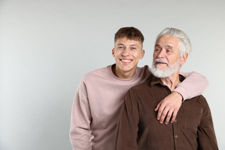 Son hugging his father on light gray background, space for textの写真素材