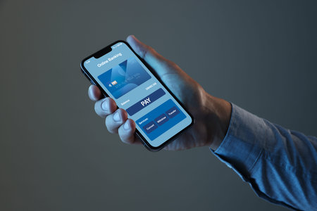 Online payment. Man holding mobile phone with open app in hand on gray background, closeup