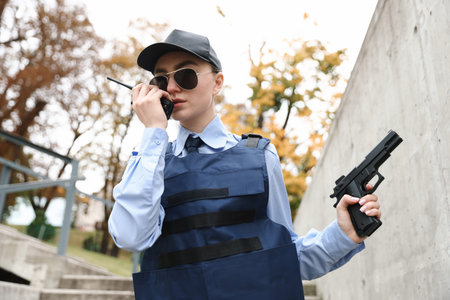 Police officer with radio and gun outdoors, low angle view