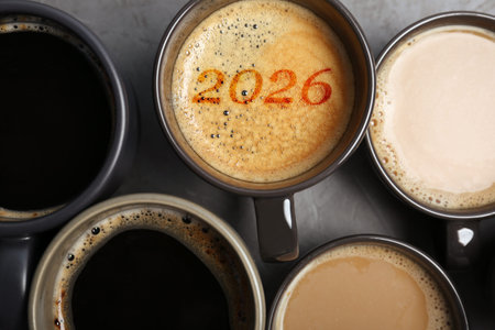 Cup of coffee with numbers among others on gray table, top view