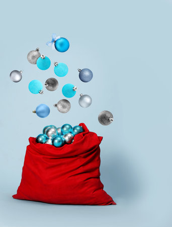 Christmas balls falling into bag on light backgroundの写真素材