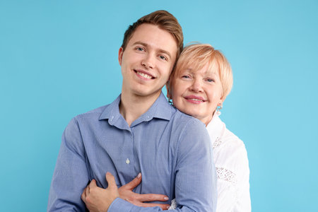 Mother hugging her son on light blue backgroundの写真素材