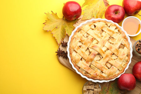 Tasty homemade apple pie and ingredients on yellow background, flat lay. Space for textの写真素材