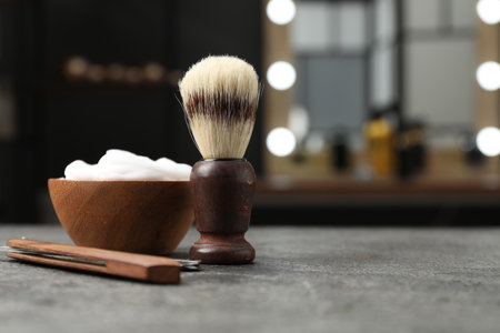 Shaving brush, foam and straight razor on gray textured table in barbershop, closeup. Space for textの写真素材