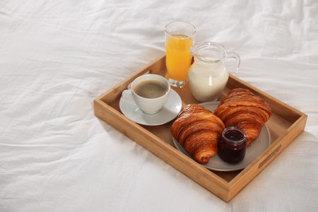 Tray with delicious breakfast on bed in hotel room, closeup. Space for textの写真素材