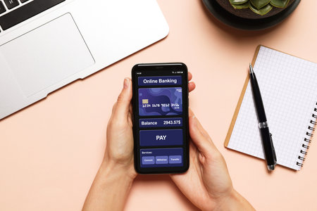 Online payment. Woman using banking app on smartphone at table, closeup