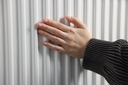 Woman warming her hands near radiator indoors, closeupの写真素材