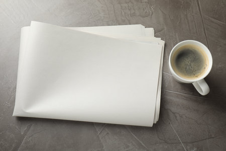 Newspaper and cup of coffee on gray table, flat lay. Mockup for designの写真素材