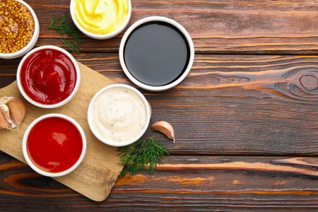 Different sauces in bowls and ingredients on wooden table, flat lay. Space for textの写真素材