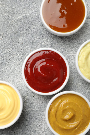 Different tasty sauces in bowls on gray table, flat layの写真素材
