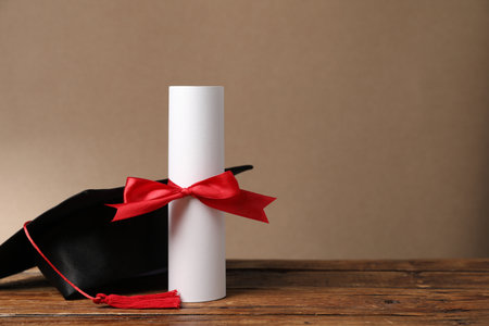 Graduation cap and diploma on wooden table, closeup.の写真素材