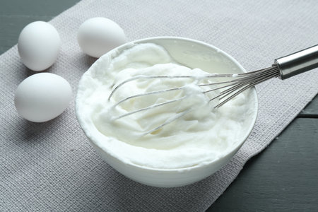 Whipped whites in bowl, eggs on gray wooden table, closeupの写真素材
