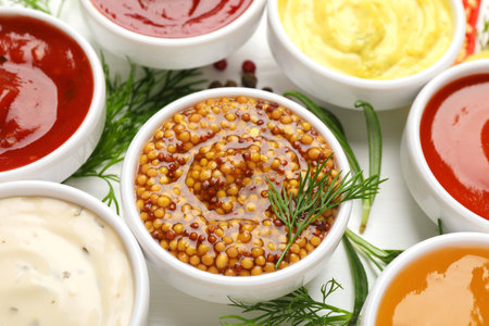 Different sauces in bowls and herbs on white table, closeupの写真素材
