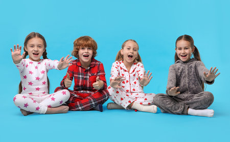 Cute children in pajamas on light blue backgroundの写真素材