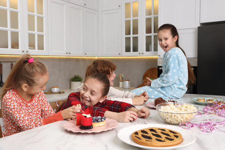 Happy children in pajamas eating treats at kitchenの写真素材