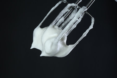 Mixer with whipped egg whites on black backgroundの写真素材
