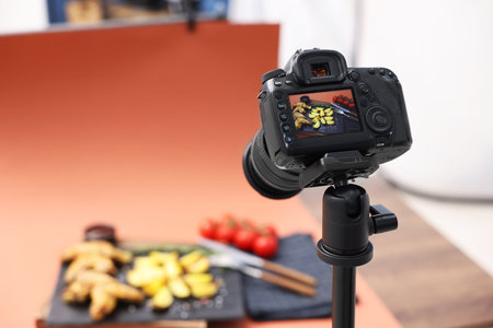 Shooting chicken wings, potato wedges, spices and tomatoes with camera in studio, selective focus. Professional food photographyの写真素材