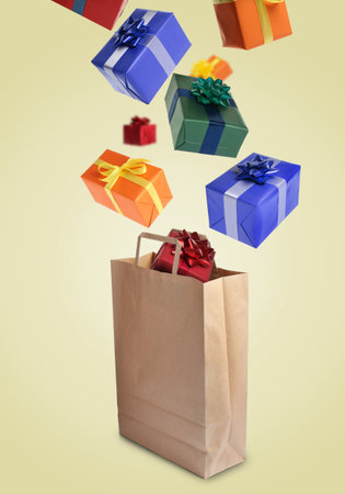 Many gift boxes falling into paper bag on dark beige backgroundの写真素材