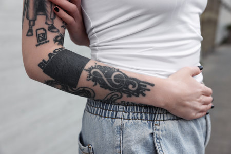 Young woman with tattoos and stylish clothes outdoors, closeupの写真素材